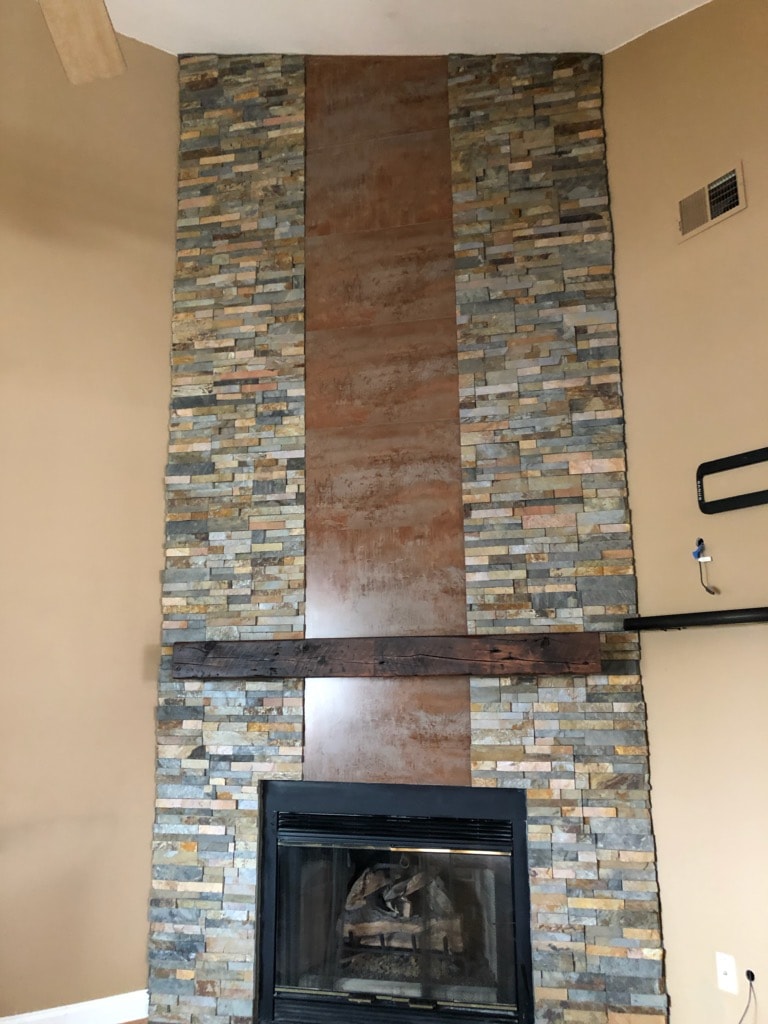 Norstone Ochre Stacked Stone Rock Panels on a corner fireplace with vertical metal insert from floor to ceiling